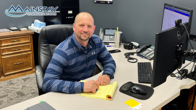 Photo of Jeremiah Duerksen sitting at his desk at Mainstay Communications